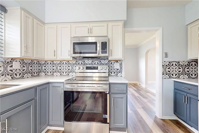 226 Cunningham Ln, Steubenville, OH 43952 - kitchen featuring appliances with stainless steel finishes, arched walkways, light countertops, tasteful backsplash, and gray cabinetry