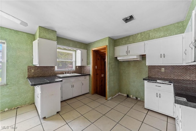 1613 Wexford Ave, Parma, OH 44134 - kitchen with a sink, under cabinet range hood, white cabinets, light tile patterned flooring, and backsplash