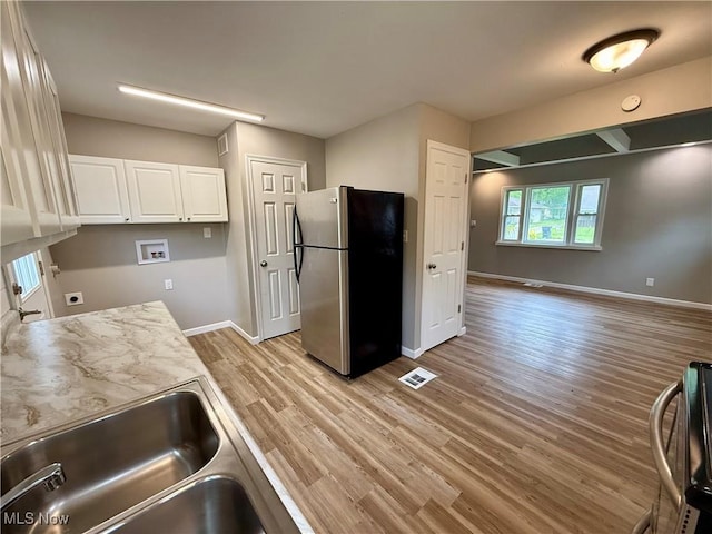 356 N Edgehill Ave, Austintown, OH 44515 - kitchen with freestanding refrigerator, white cabinets, light wood-style floors, baseboards, and a sink
