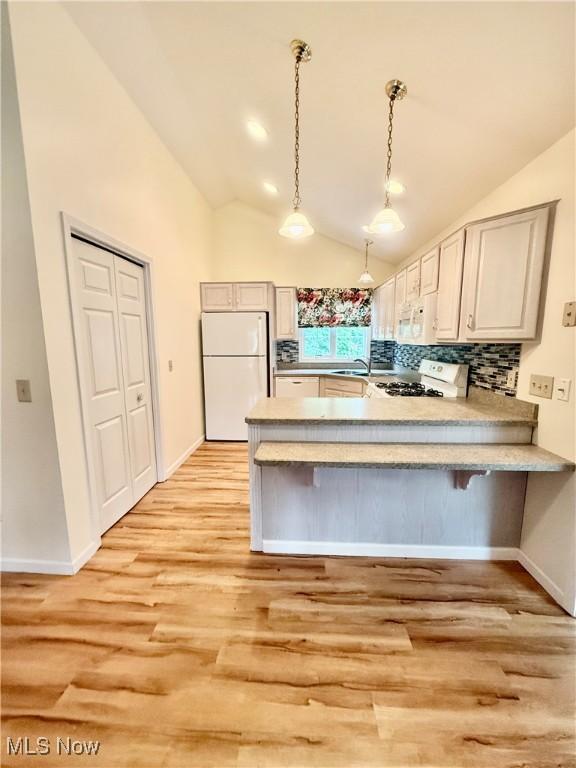 5228 Nashua Dr, Austintown, OH 44515 - kitchen featuring white appliances, a peninsula, light wood-style floors, lofted ceiling, and light countertops