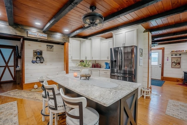 2953 State Route 225, Diamond, OH 44412 - kitchen with stainless steel fridge with ice dispenser, wood ceiling with exposed beams, wood walls, light wood-type flooring, and white cabinets
