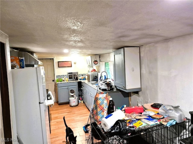 932 Logan St, East Liverpool, OH 43920 - kitchen featuring freestanding refrigerator, gray cabinets, light wood finished floors, light countertops, and a textured ceiling