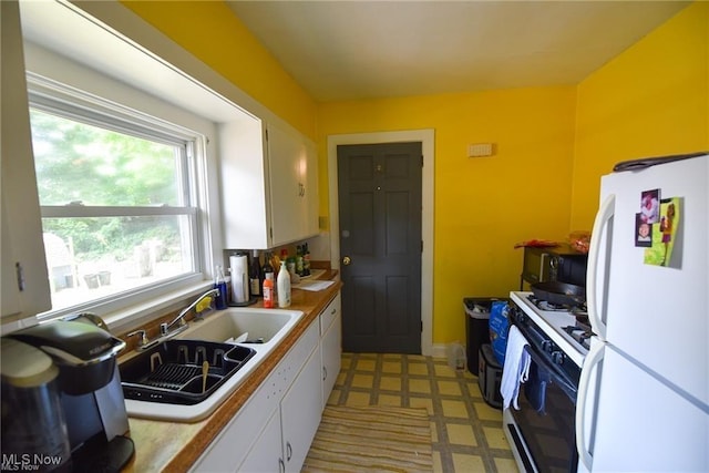 3000AND2996 Kemble Ave, Coventry, OH 44319 - kitchen with freestanding refrigerator, range with gas stovetop, white cabinetry, a sink, and light floors