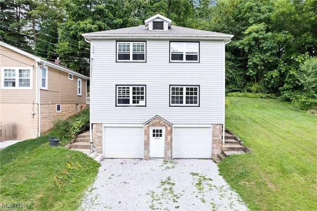 3000AND2996 Kemble Ave, Coventry, OH 44319 - view of front facade with gravel driveway, stone siding, a garage, a front lawn, and view of wooded area