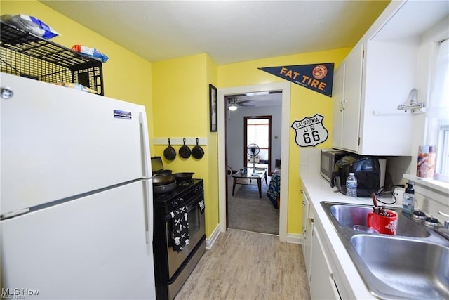 3000AND2996 Kemble Ave, Coventry, OH 44319 - kitchen with freestanding refrigerator, black range with gas cooktop, a sink, light wood-style flooring, and white cabinets