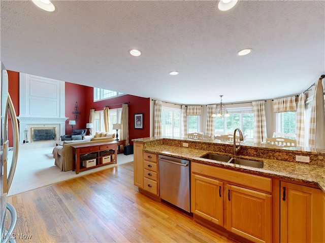 8836 Shetland Ct, Kirtland, OH 44094 - kitchen with stainless steel appliances, a sink, a textured ceiling, light stone countertops, and light wood-style flooring
