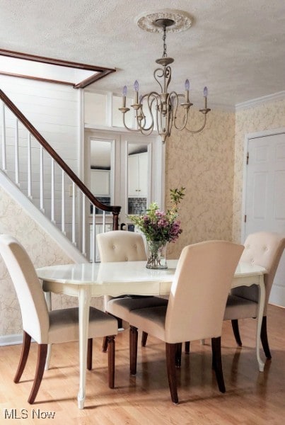 131 N Walnut St, Ravenna, OH 44266 - dining area with a chandelier, stairway, light wood-type flooring, a textured ceiling, and wallpapered walls