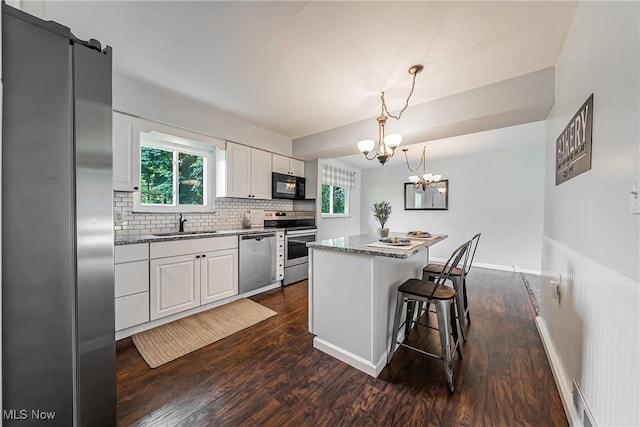 21517 Nottingham Dr, Fairview Park, OH 44126 - kitchen featuring appliances with stainless steel finishes, a chandelier, dark wood-style flooring, a kitchen island, and white cabinetry