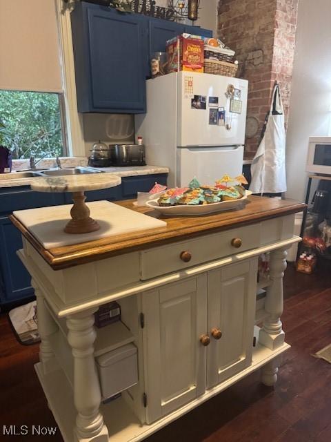 419 Commerce St, Wellsburg, WV 26070 - kitchen with freestanding refrigerator, blue cabinets, dark wood-style flooring, and light countertops