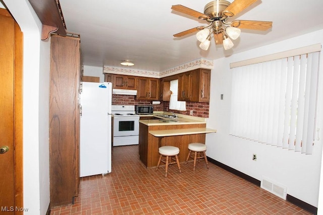 430 W Harvey St, Struthers, OH 44471 - kitchen featuring white appliances, under cabinet range hood, a peninsula, a sink, and baseboards