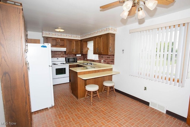 430 W Harvey St, Struthers, OH 44471 - kitchen with white appliances, under cabinet range hood, a sink, baseboards, and a peninsula