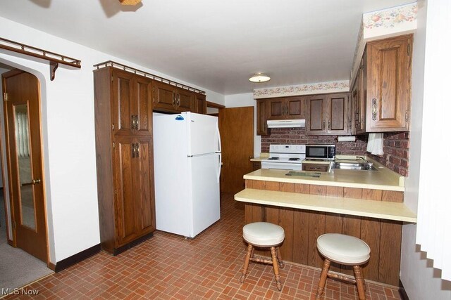 430 W Harvey St, Struthers, OH 44471 - kitchen featuring white appliances, under cabinet range hood, light countertops, a sink, and a peninsula
