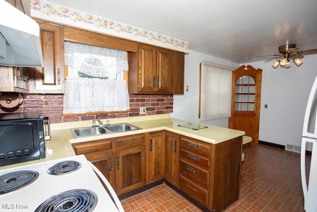 430 W Harvey St, Struthers, OH 44471 - kitchen featuring a sink, a peninsula, range hood, light countertops, and brown cabinetry