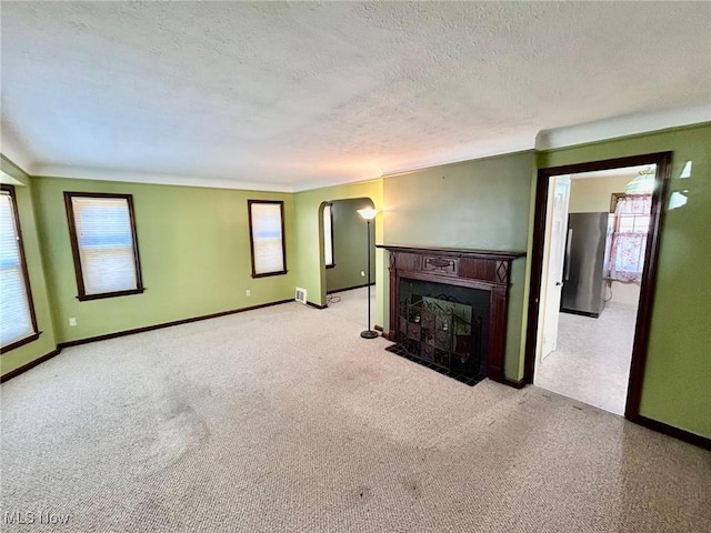 104 Sunnycliff Dr, Euclid, OH 44123 - unfurnished living room featuring a fireplace with flush hearth, baseboards, arched walkways, carpet floors, and a textured ceiling