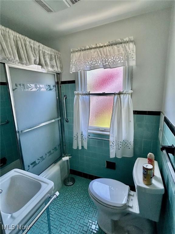 104 Sunnycliff Dr, Euclid, OH 44123 - bathroom with toilet, tile walls, shower / bath combination, a wainscoted wall, and tile patterned floors