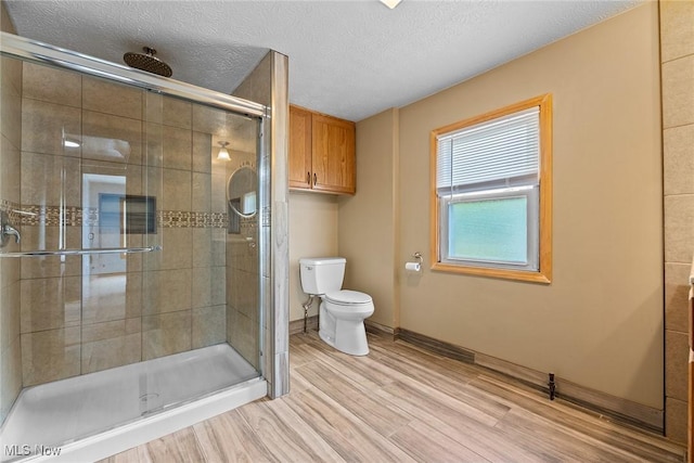 916 Kling St, Akron, OH 44311 - full bathroom with toilet, a stall shower, wood finished floors, a textured ceiling, and baseboards