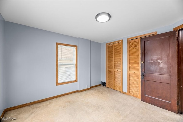 916 Kling St, Akron, OH 44311 - unfurnished bedroom with multiple closets, light carpet, and baseboards
