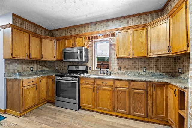 916 Kling St, Akron, OH 44311 - kitchen with stainless steel appliances, a sink, a textured ceiling, brown cabinets, and tasteful backsplash