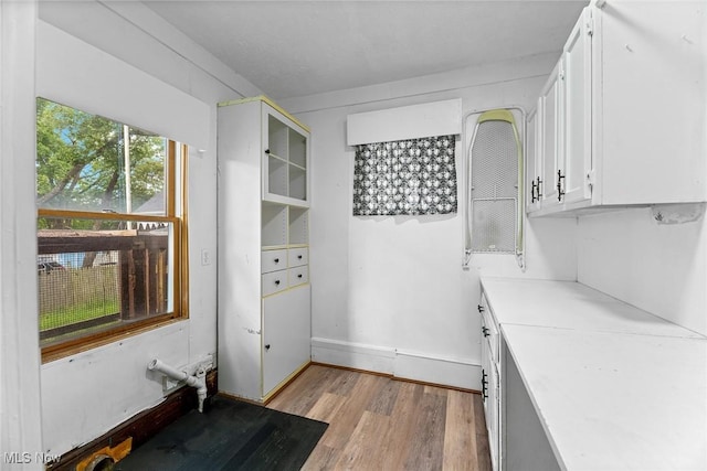 916 Kling St, Akron, OH 44311 - kitchen with light wood-style flooring, white cabinets, light countertops, baseboards, and glass insert cabinets