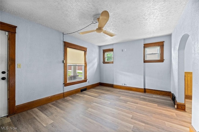 916 Kling St, Akron, OH 44311 - empty room featuring light wood-style floors, ceiling fan, arched walkways, baseboards, and a textured wall