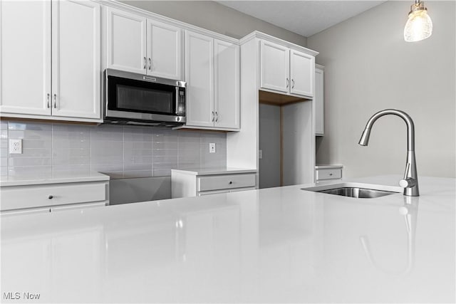 360 Bascule Dr, Lorain, OH 44052 - kitchen with stainless steel microwave, decorative backsplash, decorative light fixtures, white cabinets, and light countertops