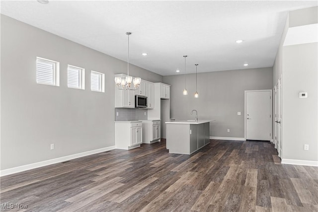 360 Bascule Dr, Lorain, OH 44052 - kitchen featuring stainless steel microwave, dark wood-type flooring, a center island with sink, white cabinets, and recessed lighting