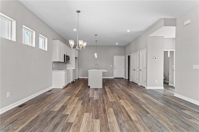 360 Bascule Dr, Lorain, OH 44052 - kitchen with stainless steel microwave, white cabinets, a chandelier, dark wood-style floors, and recessed lighting