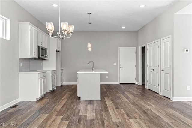 360 Bascule Dr, Lorain, OH 44052 - kitchen featuring stainless steel microwave, a chandelier, light countertops, white cabinetry, and dark wood finished floors