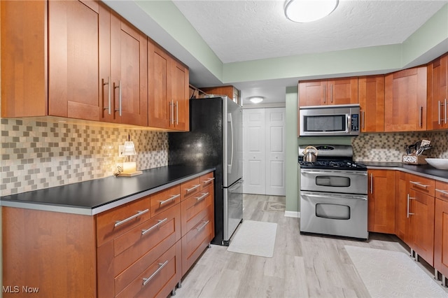 6290 Greenwood Pkwy Unit 402, Northfield, OH 44067 - kitchen with appliances with stainless steel finishes, light wood-type flooring, dark countertops, brown cabinets, and a textured ceiling