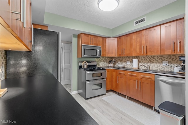 6290 Greenwood Pkwy Unit 402, Northfield, OH 44067 - kitchen with appliances with stainless steel finishes, a sink, light wood-type flooring, tasteful backsplash, and a textured ceiling