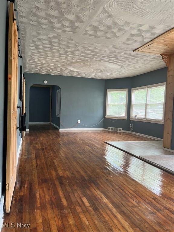 1264 Diagonal Rd, Akron, OH 44307 - spare room with arched walkways, wood-type flooring, and baseboards