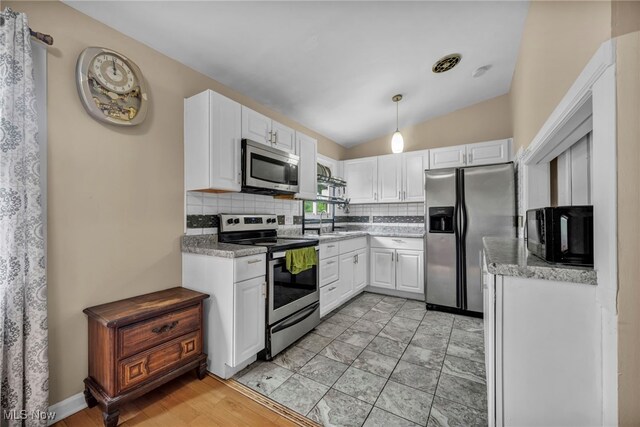 1654 Vicgross Ave, Akron, OH 44310 - kitchen featuring appliances with stainless steel finishes, backsplash, white cabinetry, lofted ceiling, and a sink