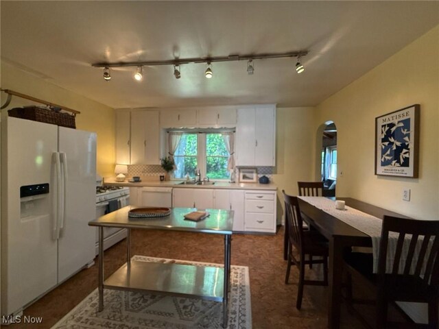 1089 Homestead Rd, South Euclid, OH 44121 - kitchen with white appliances, white cabinets, a sink, arched walkways, and backsplash
