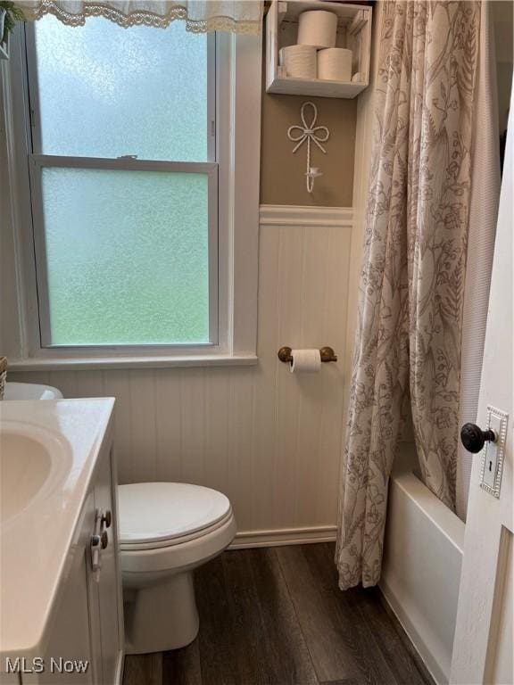724 8th St, Struthers, OH 44471 - bathroom with wood finished floors, toilet, vanity, shower / bath combo with shower curtain, and a wainscoted wall