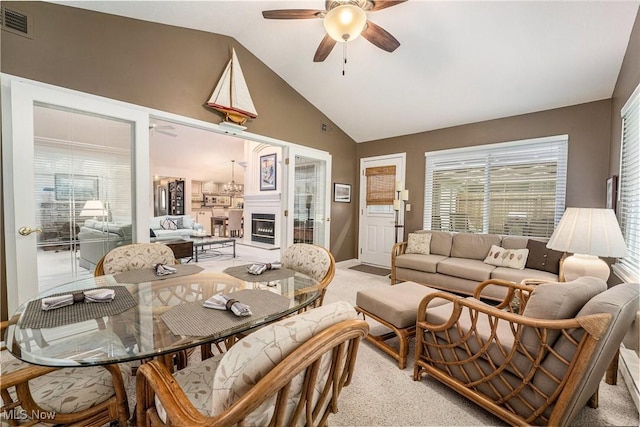 194 Lisa Ann Dr, Huron, OH 44839 - dining room with ceiling fan, light colored carpet, high vaulted ceiling, a glass covered fireplace, and baseboards