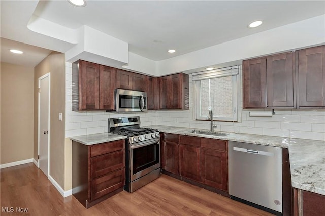 2381 Charney Rd, University Heights, OH 44118 - kitchen with appliances with stainless steel finishes, a sink, light wood-style floors, light stone countertops, and tasteful backsplash