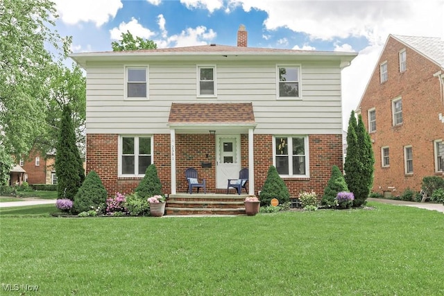 2381 Charney Rd, University Heights, OH 44118 - view of front of house with brick siding, a front yard, and a chimney