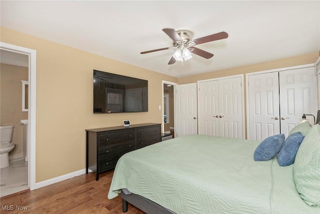 2381 Charney Rd, University Heights, OH 44118 - bedroom featuring two closets, baseboards, wood finished floors, ensuite bath, and ceiling fan