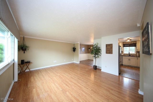 726 N Fork Way, Brunswick Hills, OH 44212 - unfurnished living room featuring light wood-style flooring, baseboards, a sink, and crown molding
