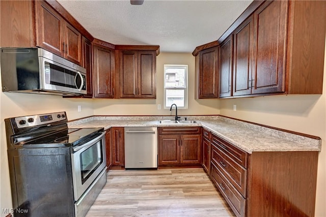 821 9th St SW, Massillon, OH 44647 - kitchen with stainless steel appliances, a sink, light wood-type flooring, light countertops, and a textured ceiling