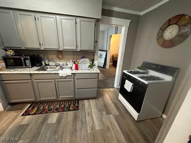 9705 Marah Ave, Cleveland, OH 44104 - kitchen with white gas range oven, stainless steel microwave, gray cabinets, wood finished floors, and a sink