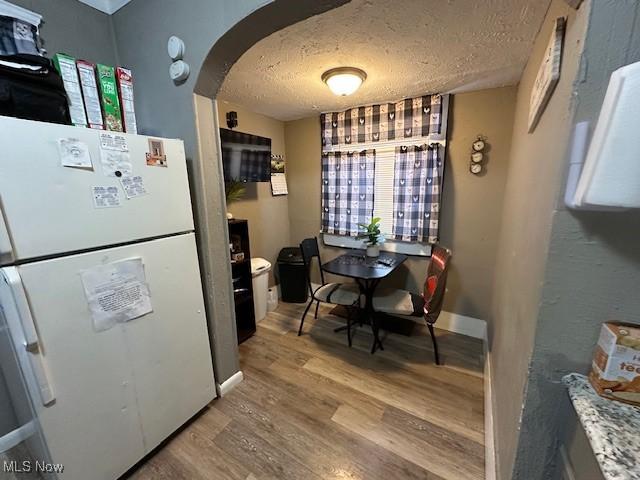 9705 Marah Ave, Cleveland, OH 44104 - kitchen featuring freestanding refrigerator, arched walkways, light wood-style floors, a textured ceiling, and baseboards