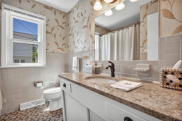 50 Luikart Dr, Euclid, OH 44123 - full bathroom with wallpapered walls, tile walls, toilet, vanity, and wainscoting