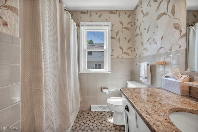 50 Luikart Dr, Euclid, OH 44123 - bathroom featuring wallpapered walls, toilet, vanity, tile walls, and a wainscoted wall