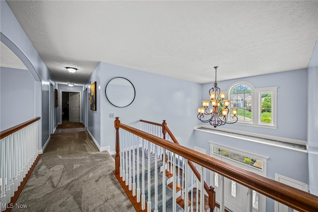 8041 Daisy Hill Ct, Concord, OH 44077 - corridor featuring an upstairs landing, a textured ceiling, carpet flooring, arched walkways, and a chandelier