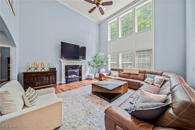 8041 Daisy Hill Ct, Concord, OH 44077 - living area featuring high vaulted ceiling, ceiling fan, wood finished floors, a fireplace with flush hearth, and crown molding