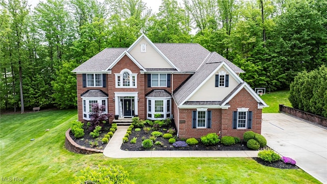 8041 Daisy Hill Ct, Concord, OH 44077 - colonial-style house with brick siding, concrete driveway, a front lawn, view of wooded area, and a shingled roof