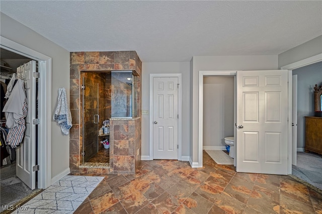 8041 Daisy Hill Ct, Concord, OH 44077 - bathroom with a stall shower, a textured ceiling, a walk in closet, toilet, and stone finish flooring