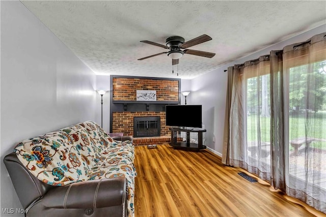 378 Stahl Ave, Cortland, OH 44410 - living area featuring a textured ceiling, a ceiling fan, wood finished floors, a brick fireplace, and baseboards