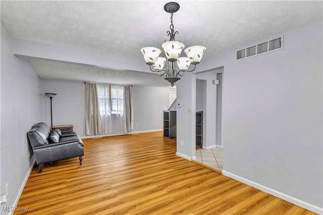 378 Stahl Ave, Cortland, OH 44410 - unfurnished room with a chandelier, a textured ceiling, light wood-style floors, and baseboards